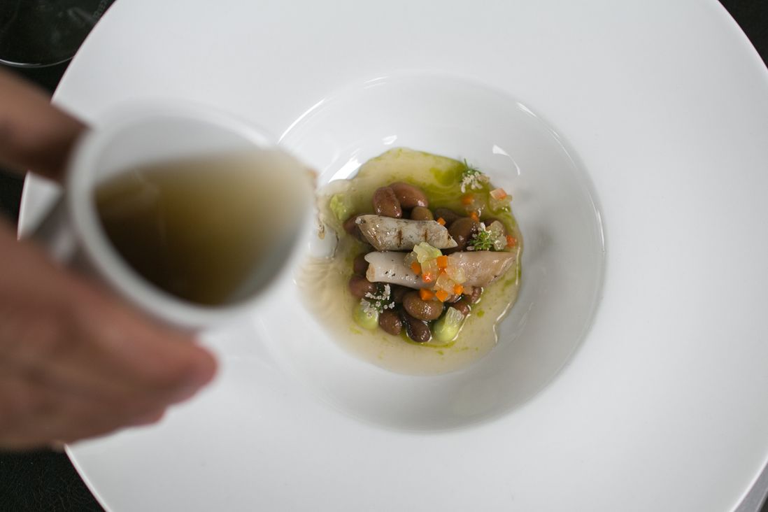 Kostow pours broth over rancho gordo beans and razor clams<br/>